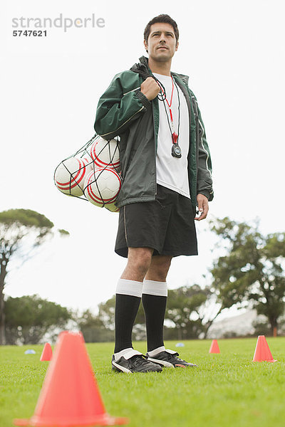 Trainer mit Fußbällen auf dem Spielfeld