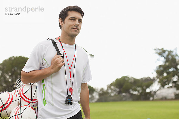 Trainer mit Fußbällen auf dem Spielfeld