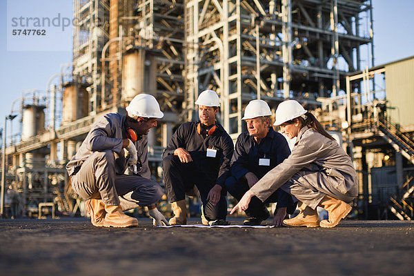 Arbeiter mit Blaupausen in der Ölraffinerie