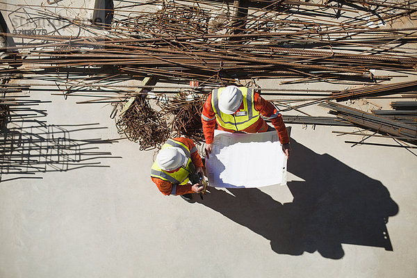 Arbeiter beim Lesen von Bauplänen vor Ort