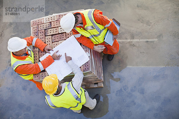 Arbeiter beim Lesen von Bauplänen vor Ort