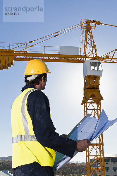 Arbeiter beim Lesen von Bauplänen vor Ort