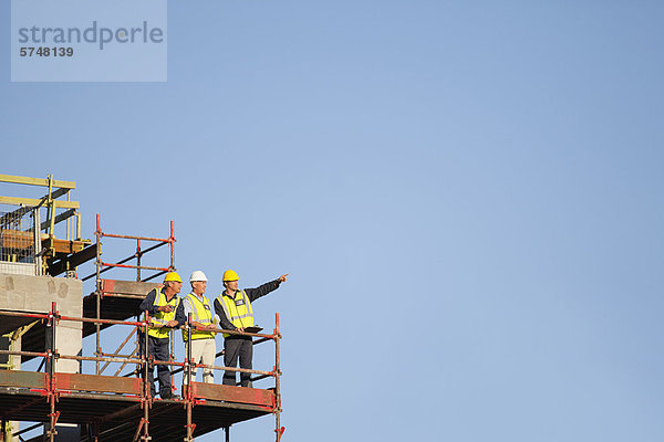 Arbeiter stehen auf Gerüsten auf der Baustelle