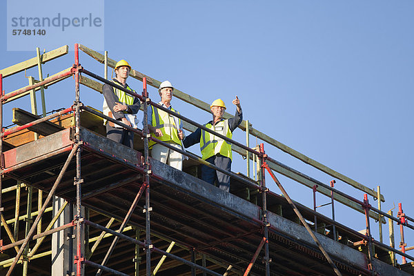 Arbeiter stehen auf Gerüsten auf der Baustelle