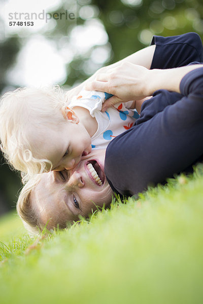 Mutter und Baby spielen im Gras