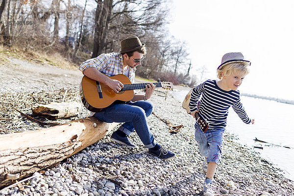 Vater und Sohn mit Gitarren am Bach