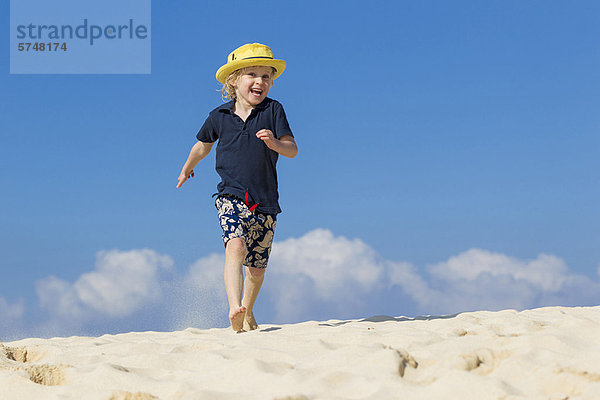 Junge geht am Sandstrand spazieren