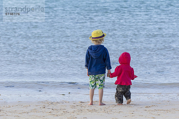 Kinder halten Hände am Sandstrand