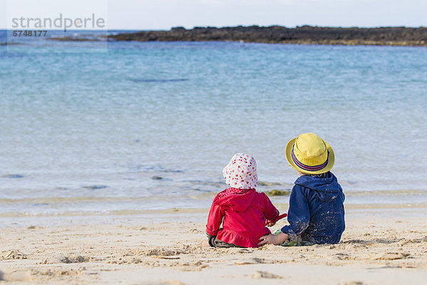 Kinder sitzen am Sandstrand