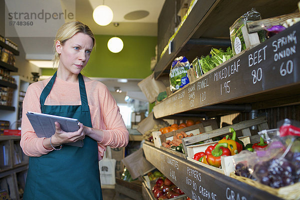 Lebensmittelhändler mit Tablet-Computer im Geschäft
