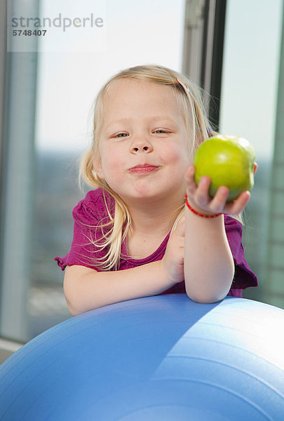 Mädchen essen Apfel auf Übungsball