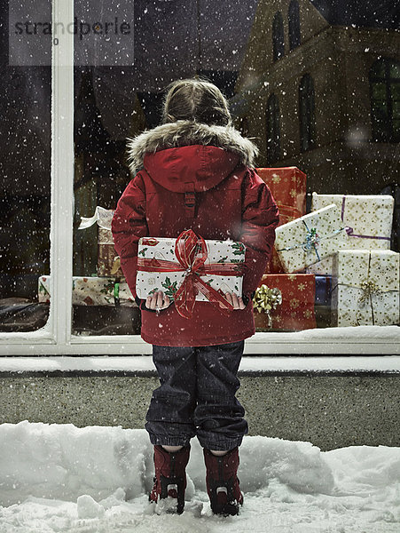 Mädchen mit Weihnachtsgeschenk im Schnee