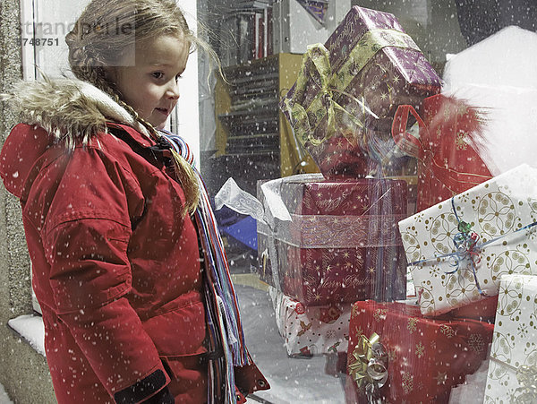 Mädchen bewundert Weihnachtsgeschenke im Schnee