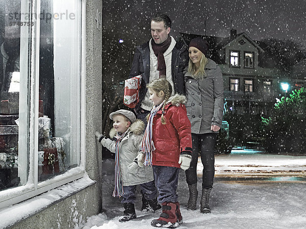 Familie bewundert Weihnachtsfenster im Schnee