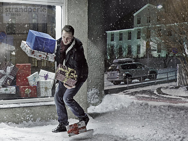 Mann  der Weihnachtsgeschenke im Schnee fallen lässt