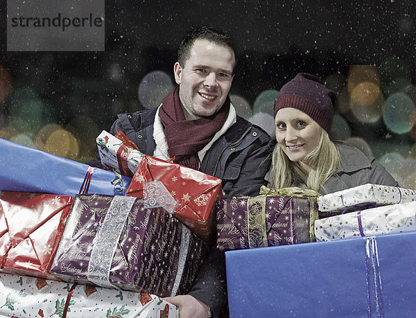 Paar mit Weihnachtsgeschenken im Schnee