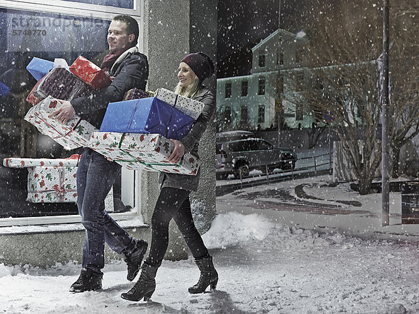 Paar mit Weihnachtsgeschenken im Schnee