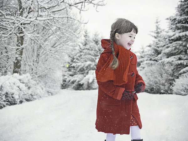 Lächelndes Mädchen spielt im Schnee