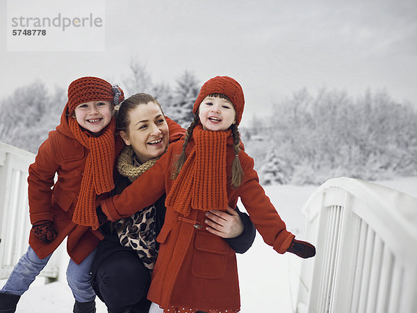 Mutter und Töchter beim Spielen im Schnee