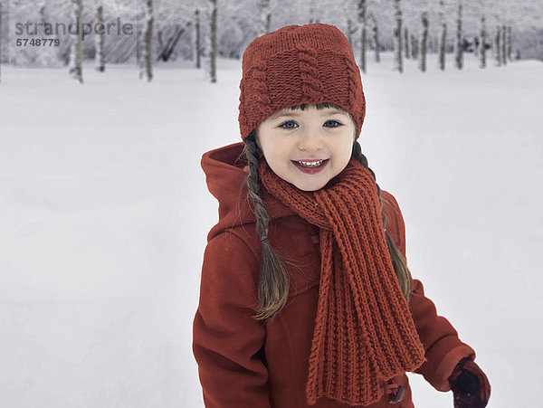 Lächelndes Mädchen spielt im Schnee