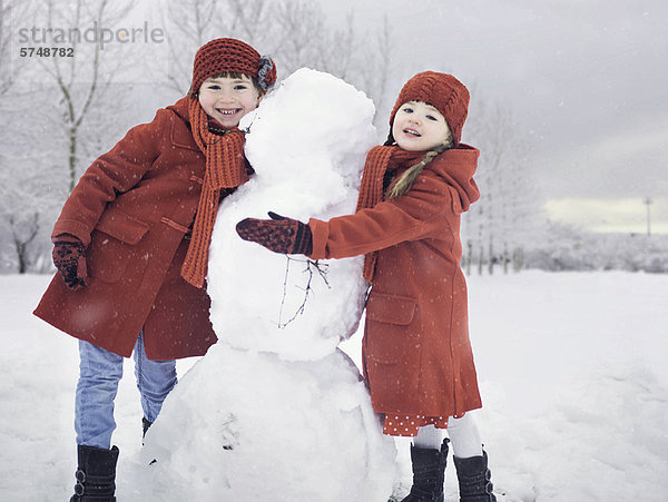 Mädchen bauen Schneemann im Freien