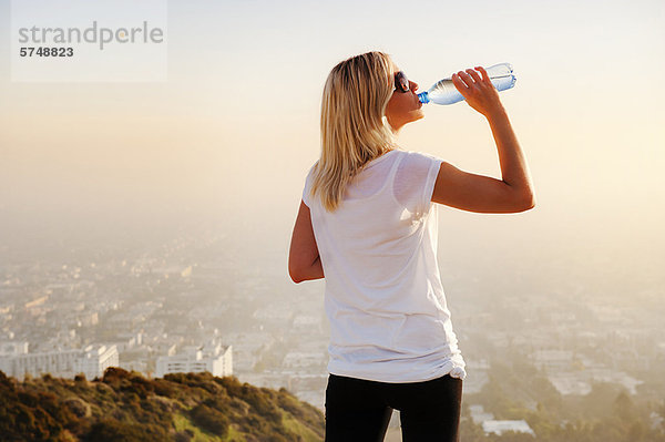 Frau trinkt Wasser auf dem Hügel