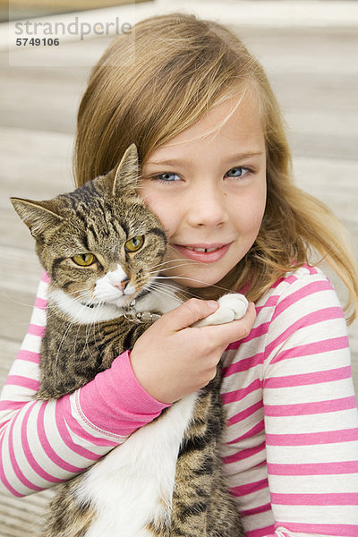 Lächelndes Mädchen hält Katze im Freien