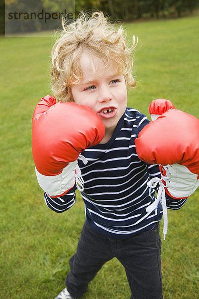 Junge spielt mit Boxhandschuhen im Freien