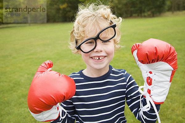 Junge spielt mit Boxhandschuhen im Freien