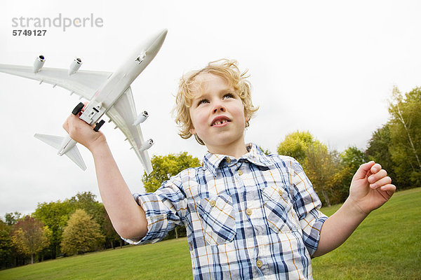 Junge spielt mit Spielzeugflugzeug im Freien