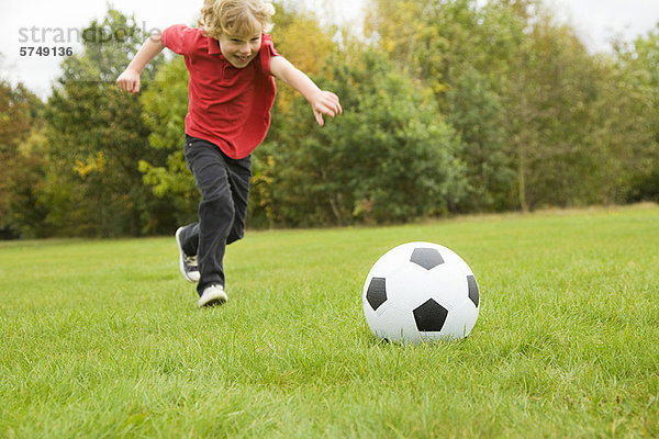 Junge spielt mit Fußball im Feld