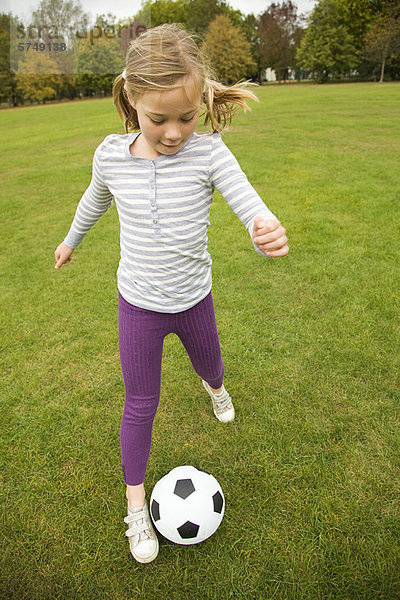 Mädchen spielt mit Fußball im Feld