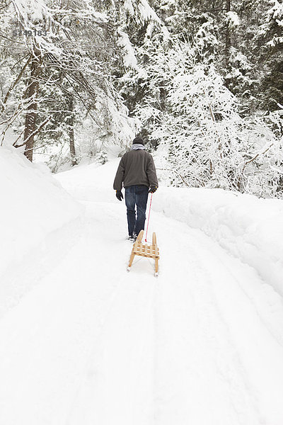 Mann zieht Schlitten im Schneefeld
