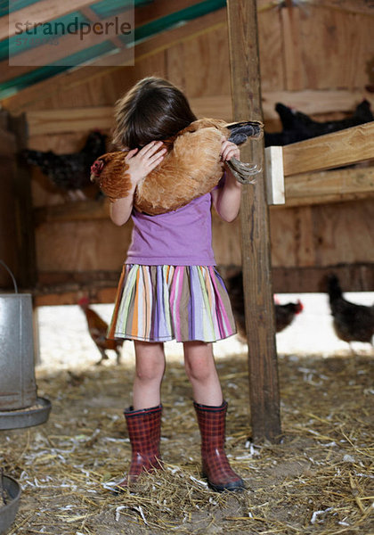 Mädchen hält Henne im Hühnerstall