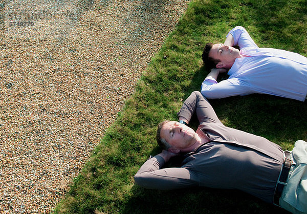 Zwei Geschäftsleute schlafen auf Gras