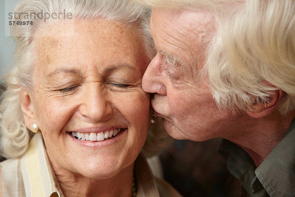 Senior Mann küsst Seniorin auf Wange