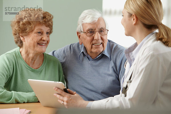 Arzt mit digitalem Tablett und Seniorenpaar