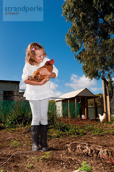Mädchen hält ein Huhn in der Hand