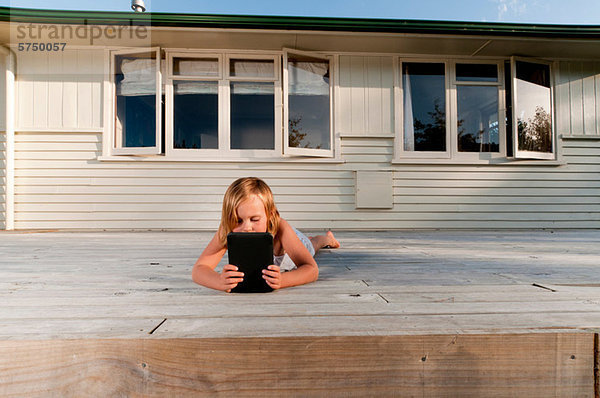 Girl on porch  reading electronic book