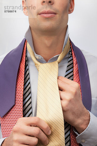 Junger Mann beim Anprobieren von Krawatten