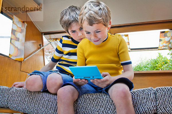 Zwei Jungen spielen Handheld-Videospiel