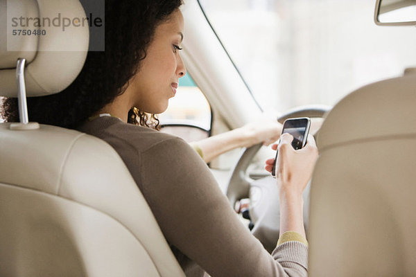 Junge Frau SMS auf dem Handy vom Auto aus