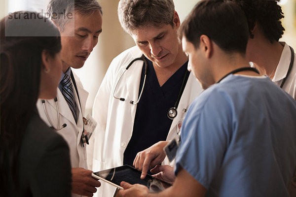 Ärzte diskutieren Patientendiagramme auf digitalem Tablett im Krankenhaus