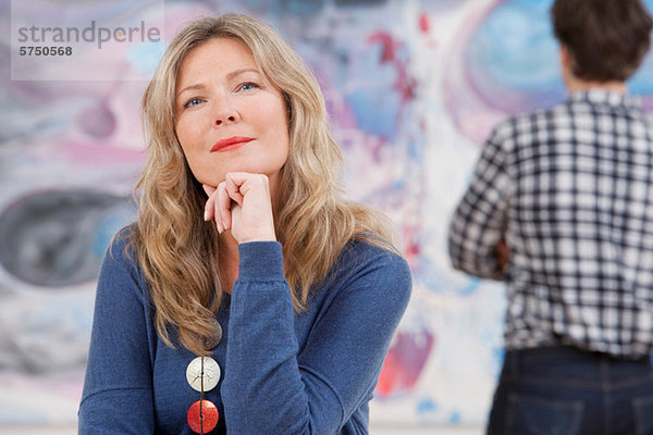 Mittlere erwachsene Frau sitzend vor dem Ölgemälde in der Galerie