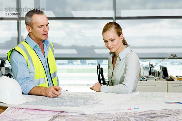 Ingenieur mit Architekt beim Betrachten von Bauplänen im Büro