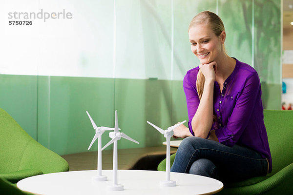 Junge Frau betrachtet Modell einer Windkraftanlage