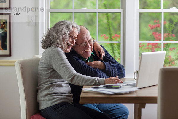 Senior Paar mit Laptop zu Hause  lachend