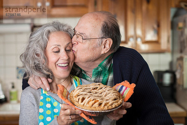 Senior Mann küssende Frau mit frisch gebackenem Kuchen