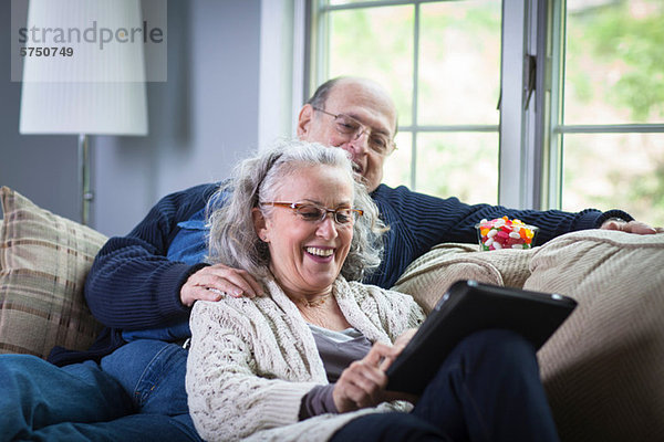 Senior Paar mit digitalem Laptop auf dem Sofa zu Hause