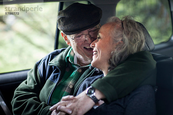Seniorenpaar umarmt sich hinten im Auto